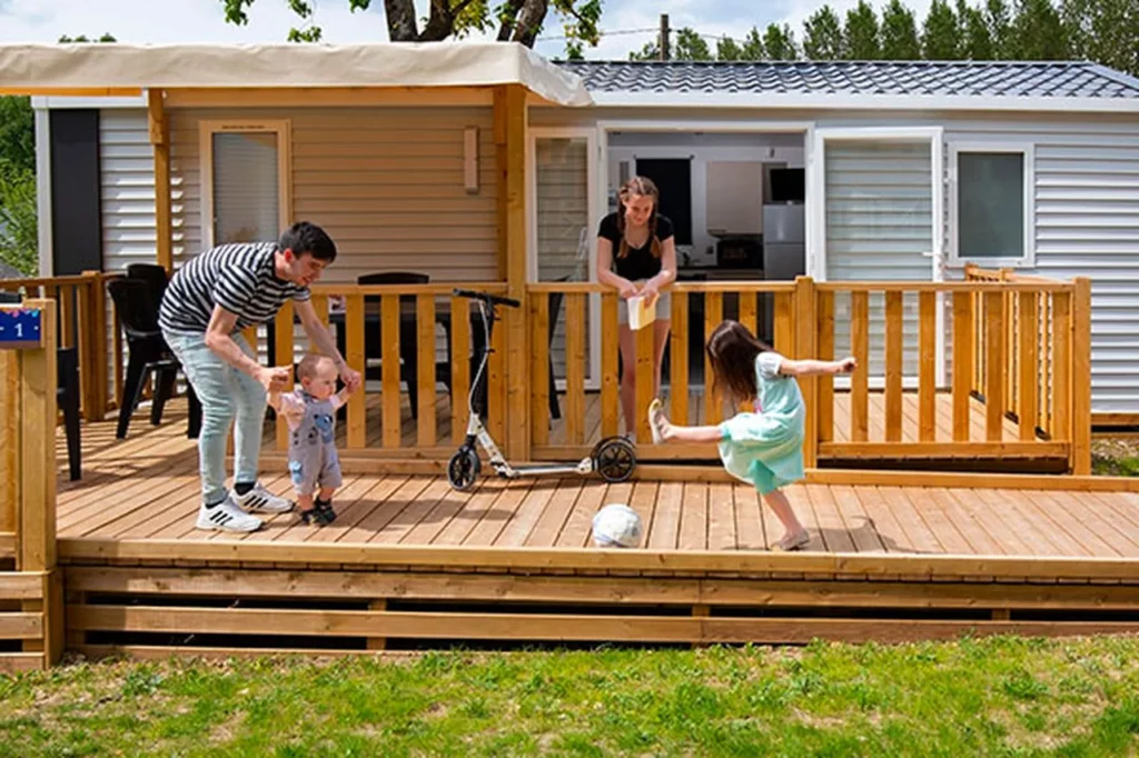 famille qui joue sur la terrasse d'un mobile home du camping