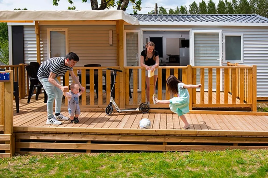 Spelend gezin op het terras van een stacaravan van de camping