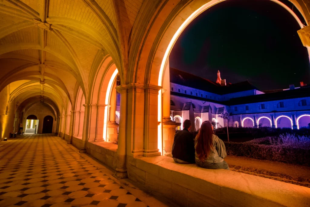 Royal Abbey of Fontevraud, couple looks at the inner courtyard at night after a day at the campsite of Anjou Nobis